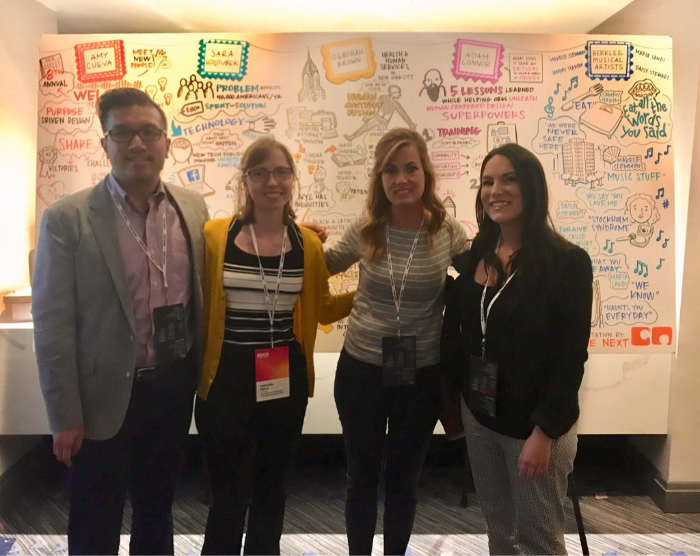 four team members standing in front of a whiteboard for a photo