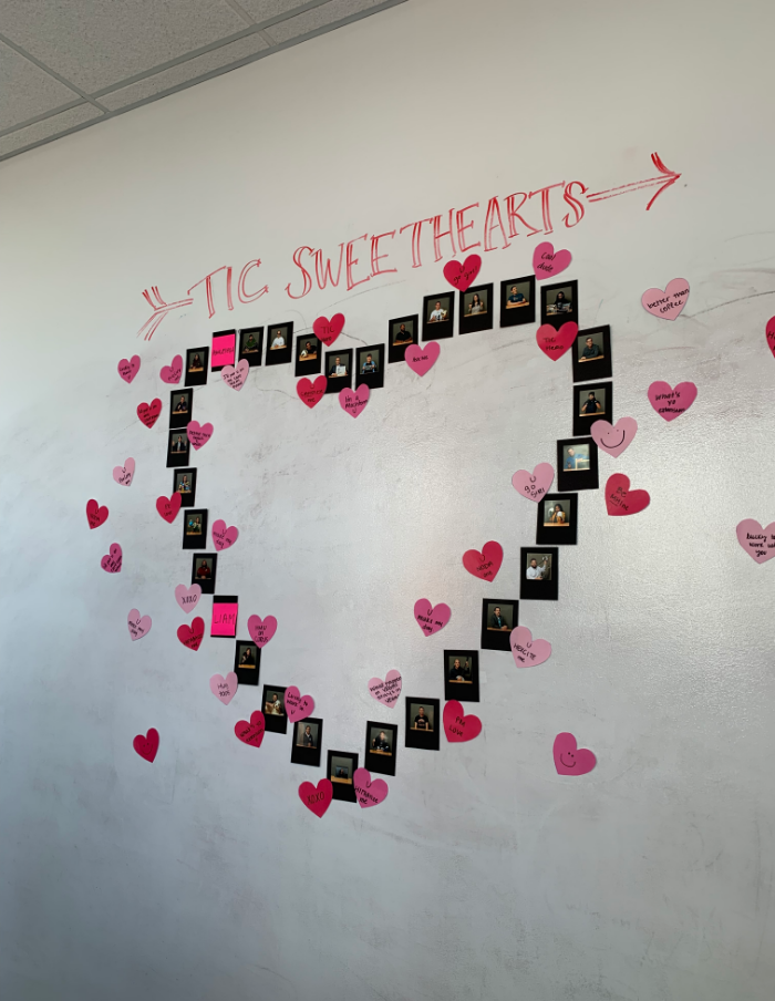 a whiteboard with team member photos outlined in a heart for Valentine's day